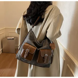Stylish grey denim-textured hobo shoulder bag with brown leather pockets on model.