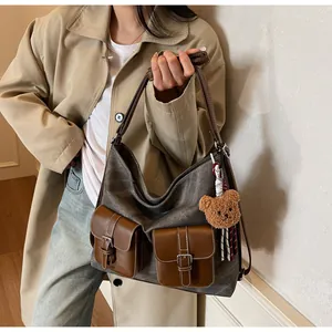 Stylish hobo shoulder bag featuring denim texture and brown leather front pockets
