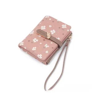 Detailed view of women's short pink floral wallet featuring wristlet strap and leaf snap