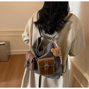 Detailed view of fashionable denim texture women's backpack with cute teddy bear charm