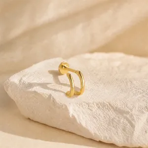 Detailed side view of a minimalist double-layer C-shape gold labret stud earring on stone
