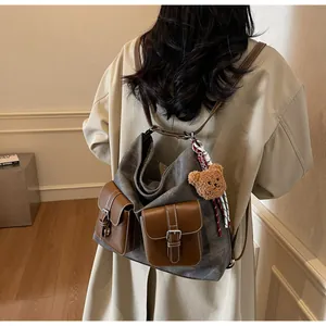 Back view of a stylish denim texture backpack with leather pockets on a model in a trench coat