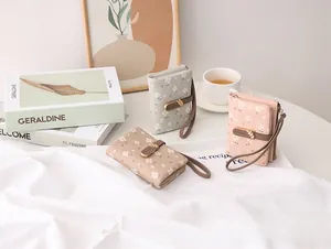 Three floral print short wallets in pastel colors with wristlet straps and gold leaf buckle.