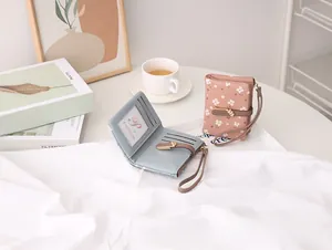 Detail of floral women's bifold wallet with multi-card slots and wristlet strap