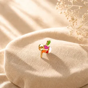 Close-up detail of a colorful enamel snake stud earring on a textured beige linen fabric