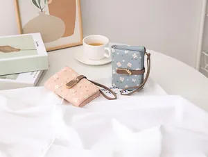 Close-up of small floral print wallets with wristlet strap and gold leaf clasp detail