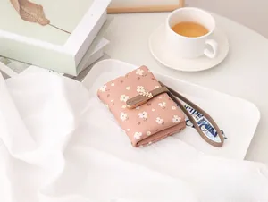 Close-up of a pink floral printed short wallet featuring an elegant leaf buckle and strap.