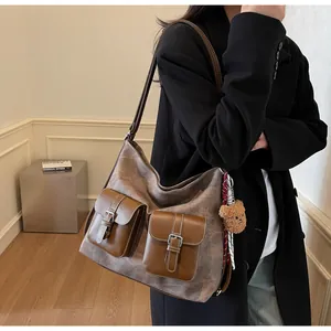 Close-up of fashion denim texture shoulder bag with brown buckle pockets and bear charm.