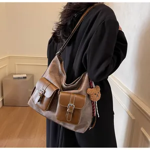Detailed view of a vintage denim texture brown tote bag with cute teddy bear charm on a model