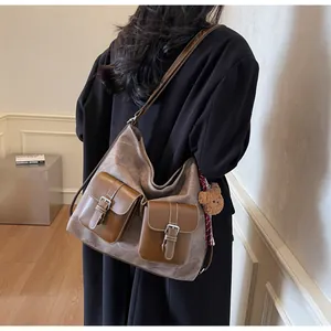 Large vintage brown hobo shoulder bag with denim texture and front pockets on model