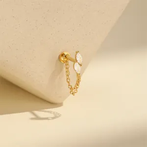 Macro view of gold cartilage piercing stud featuring marquise gems and a chain.