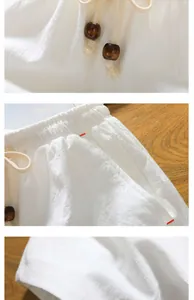 Detailed view of white breathable fabric shorts showing drawstring with wood beads.