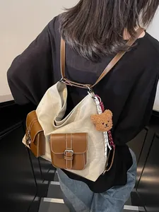 Large beige canvas hobo bag with brown faux leather pockets and a cute bear charm