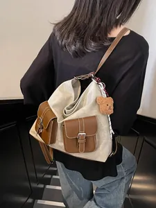 Stylish canvas backpack with denim texture and brown pockets worn by a person in a hallway