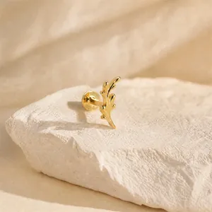 Macro detail of an elegant 16G gold leaf-shaped cartilage piercing labret stud on stone