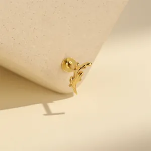 Macro detail of a golden leaf-shaped cartilage stud earring with a secure screw back.
