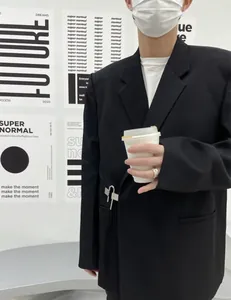 Model wearing a black oversized casual blazer with unique metal clip closure.