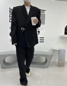 Stylish man wearing a black oversized casual suit set with a unique metal clip closure