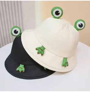 Detailed close-up view of cute cartoon frog bucket hats in cream and black colors