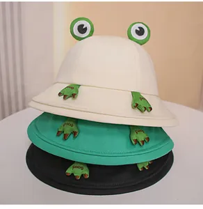 Detail view of stacked cute cotton frog bucket hats in cream, green, and black.