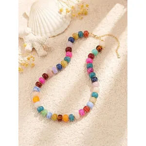 Bohemian colorful resin beaded necklace displayed on a textured background with shells