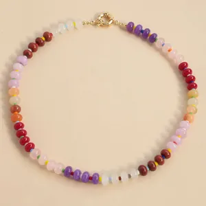 Colorful natural stone beaded choker necklace with gold spring ring clasp on beige background