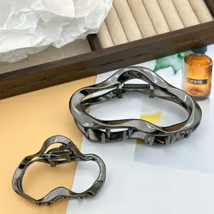 Irregular metallic wave cloud hair clips in gunmetal finish, showing two sizes at detail.