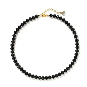 Detailed view of elegant black faceted beaded necklace with gold chain and heart charm.