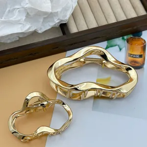 Detailed macro view of irregular wavy cloud-shaped gold metal hair claw clips.