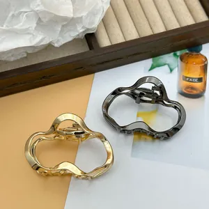 Detail of irregular cloud-shaped metal hair claw clips in gold and gunmetal.