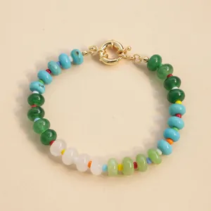Detail of a colorful natural stone beaded bracelet with a shiny gold spring clasp.