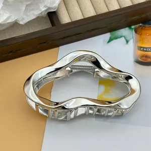 Detailed view of irregular cloud-shaped silver metal hair claw clip with glossy finish