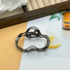 Detail view of metallic gun-metal hair claw clip with irregular cloud line design
