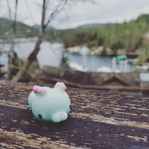 Close-up of a small mint green animal squishy toy on a rustic wooden surface.