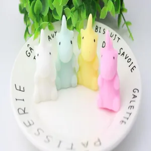 Cute set of multi-colored unicorn squishy stress relief toys on a white ceramic plate.
