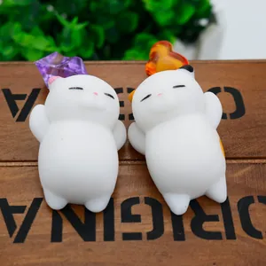 Detailed macro view of two white soft TPR squishy cat toys on a rustic wooden base