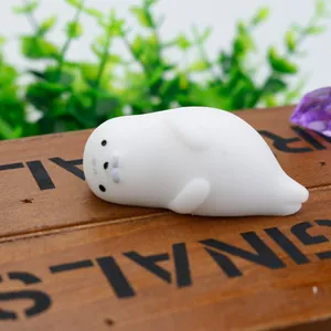 Close-up view of a soft white seal-shaped TPR squishy toy resting on a rustic wooden box.