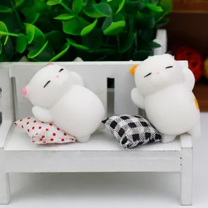Close-up of cute white cat squishy toys resting on a miniature white bench.
