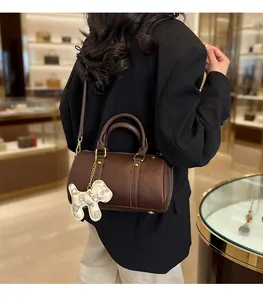 Detailed view of premium brown Boston pillow bag with stylish dog charm accessory
