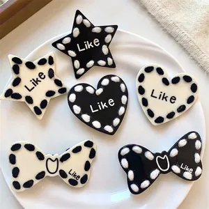 Black and white star and heart hair clips with knitted edges set on a white plate