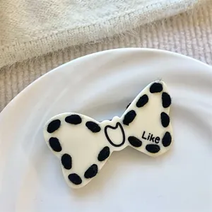 Detail showing a black and white bow hair clip with wool texture on a white plate