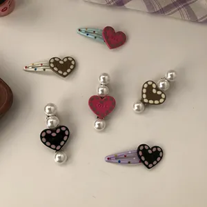 Macro view of cute heart-shaped hair clips with pearl accents and LOVE engraving