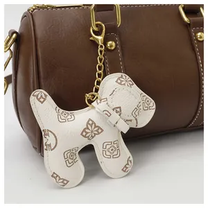Close-up detail of brown faux leather Boston bag featuring a white dog-shaped charm