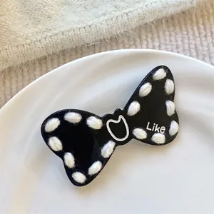 Black and white bow hair clip featuring white knitted wool edges and a heart motif