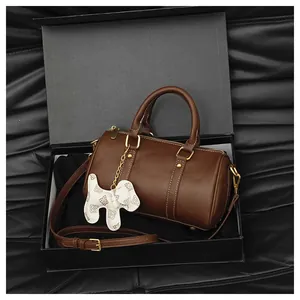 Elegant brown Boston pillow handbag with white dog charm presented in a premium black box