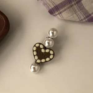 Detailed close-up of a vintage brown heart hair clip decorated with large white pearls