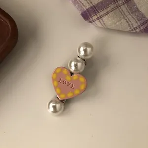 Close-up detail of a sweet pink heart-shaped hair clip with pearls and LOVE engraving