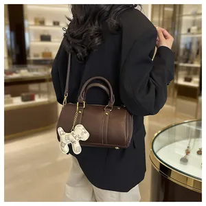 Elegant brown Boston pillow handbag with cute dog charm worn by a woman in boutique