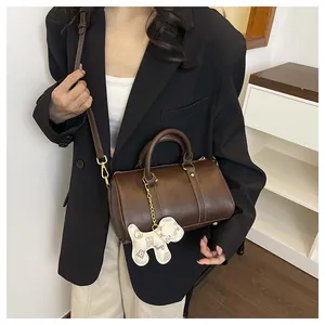 Detail of brown leather Boston pillow bag with cute dog charm and white stitching