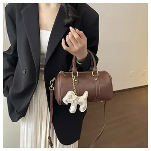 Chic brown Boston pillow bag featuring a decorative dog charm and gold hardware